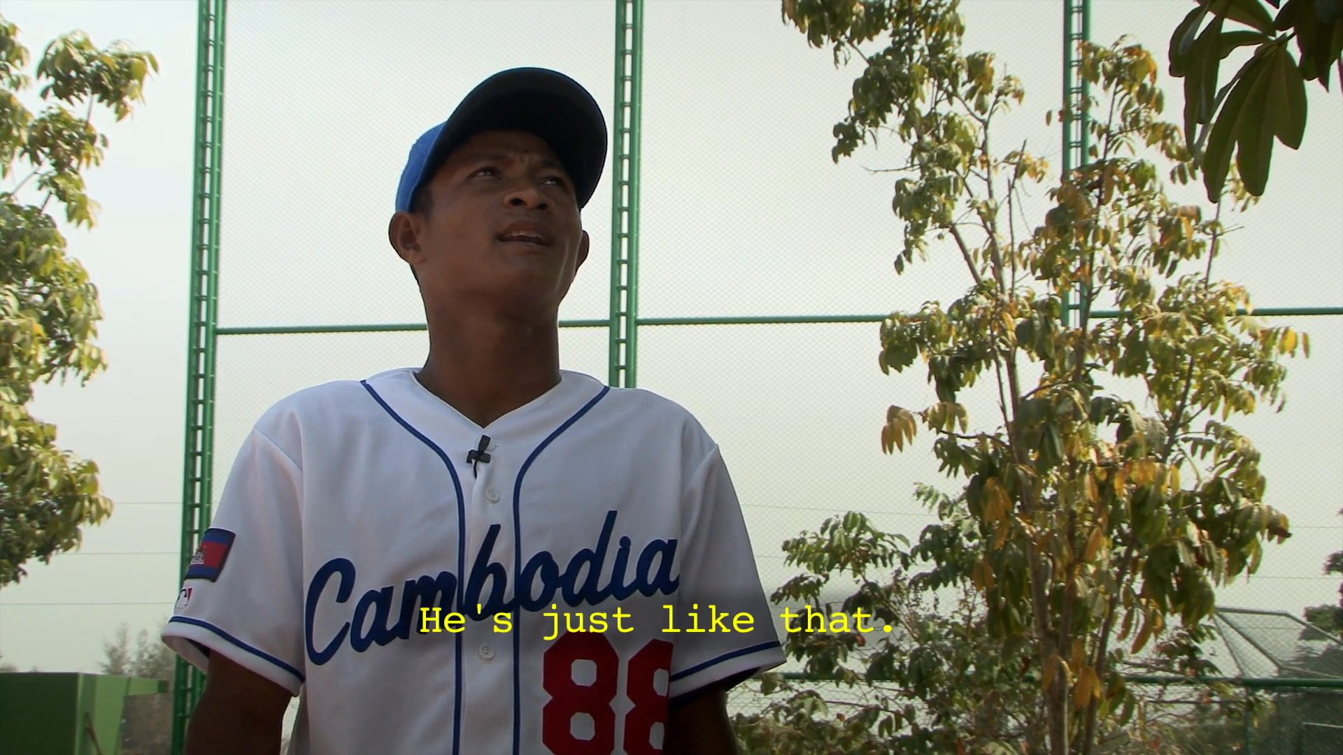 Players and coaches of the Cambodian baseball team provide personal testimony regarding team dynamics and individual temperaments during on-camera interviews at a sports facility.