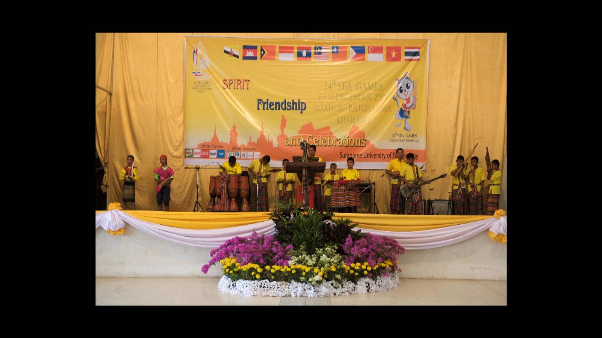Students participate in a formal international friendship ceremony, transitioning to footage of a lone individual navigating a small boat on a river in Bangkok.
