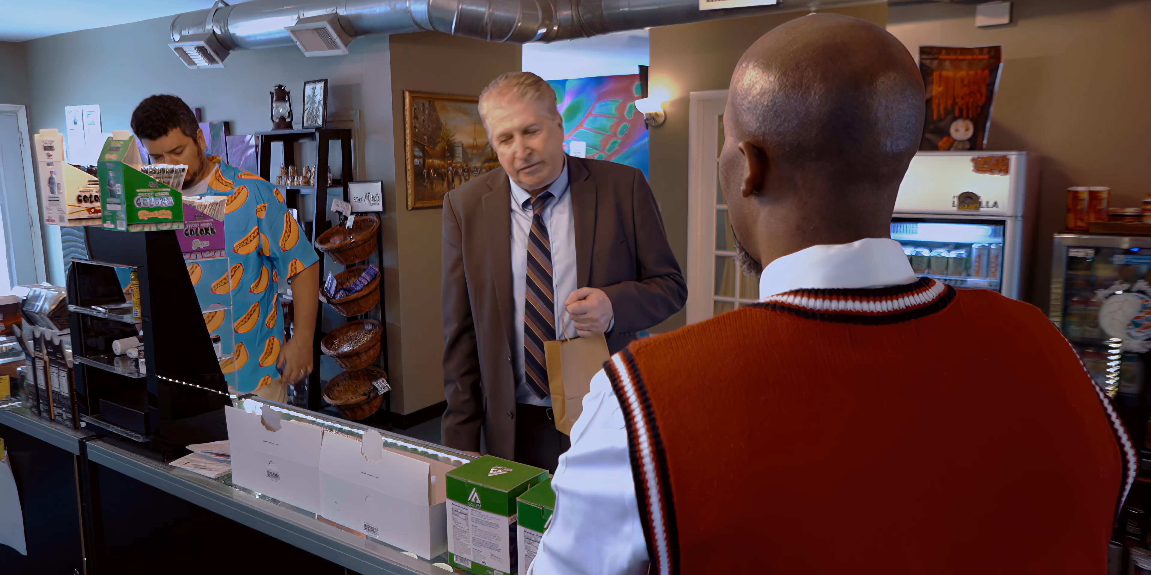 An employee assists customers at a service counter in a retail environment while managing routine transactions.