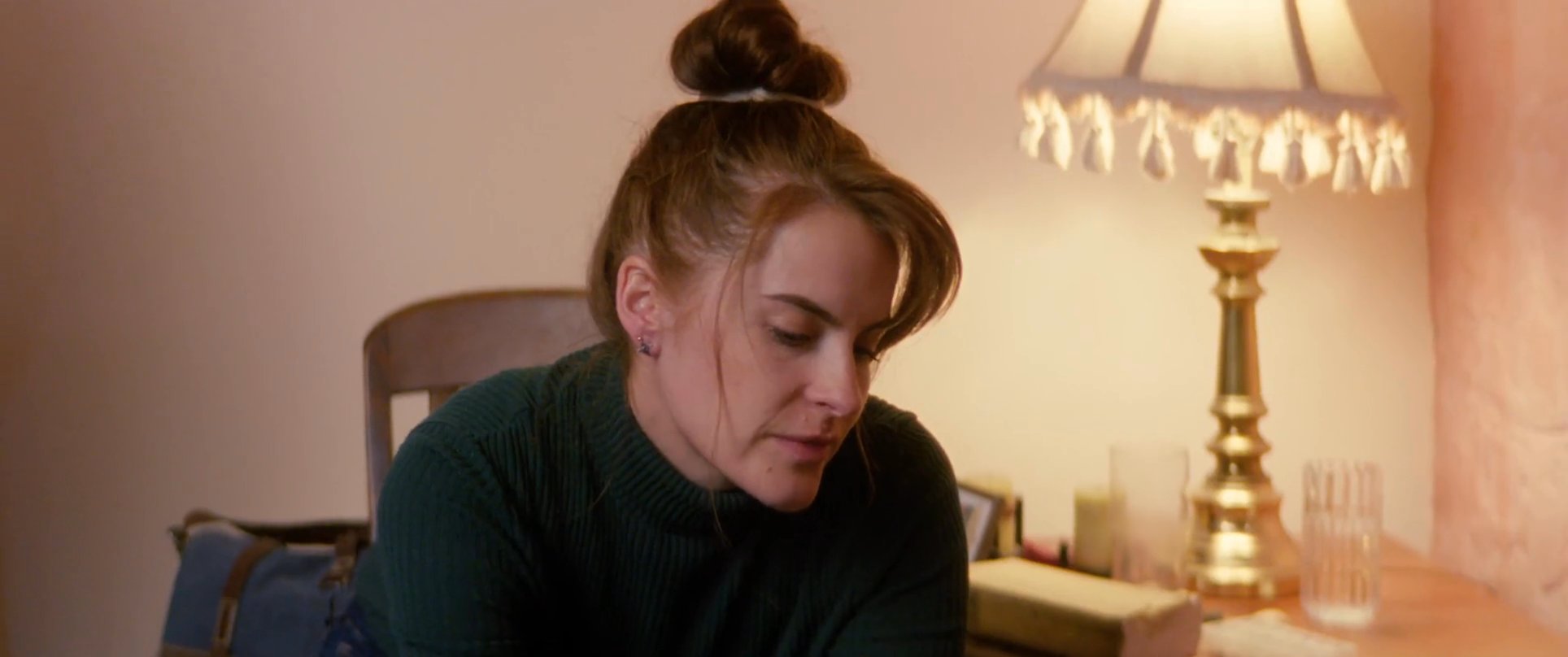 A caregiver provides emotional and physical support to an ill individual resting in a domestic bedroom setting. The interaction highlights a moment of quiet connection and care between the two subjects.