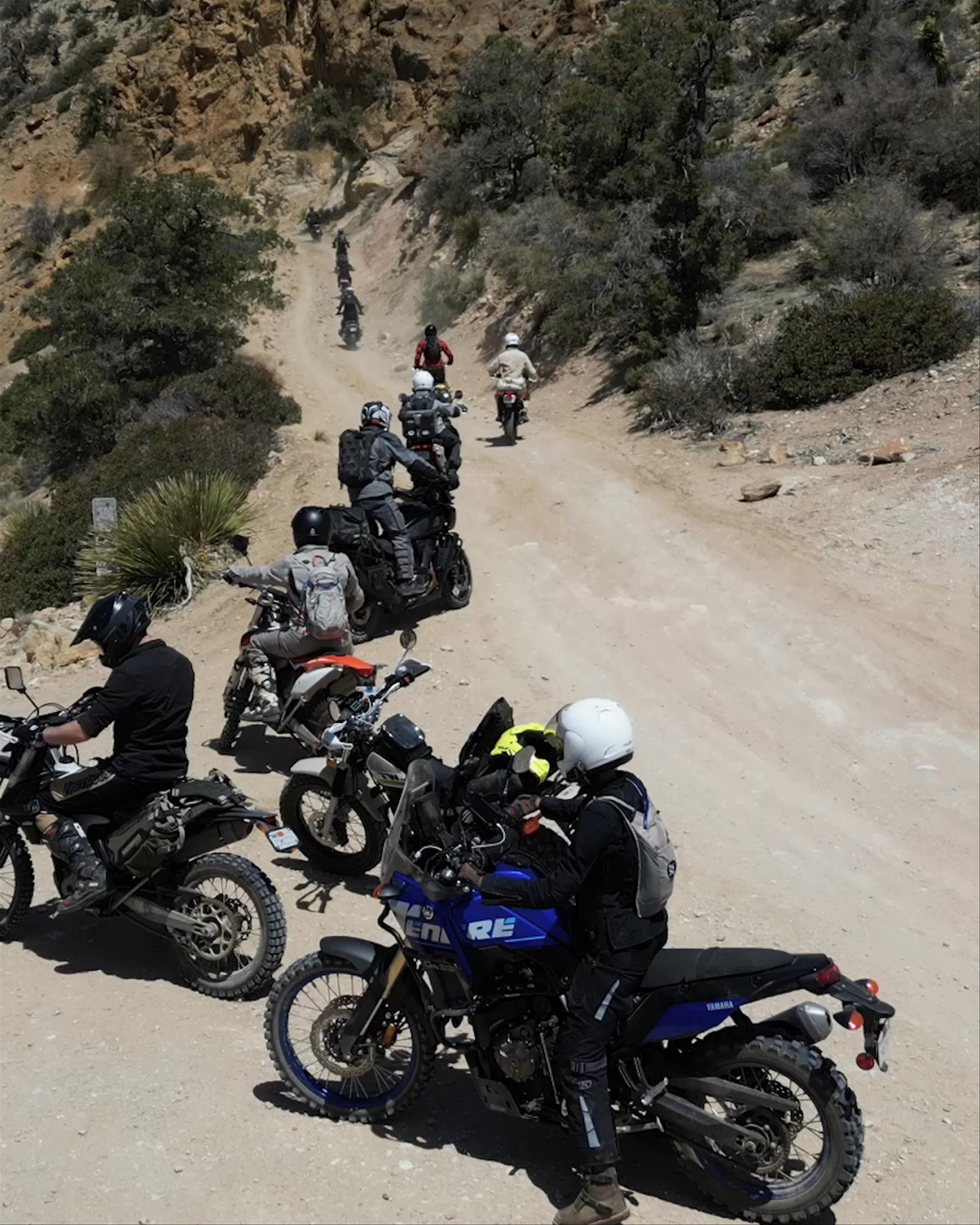 Drone view of motorcyclists riding through desert mountain path