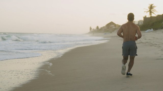 El hombre está trotando en la playa