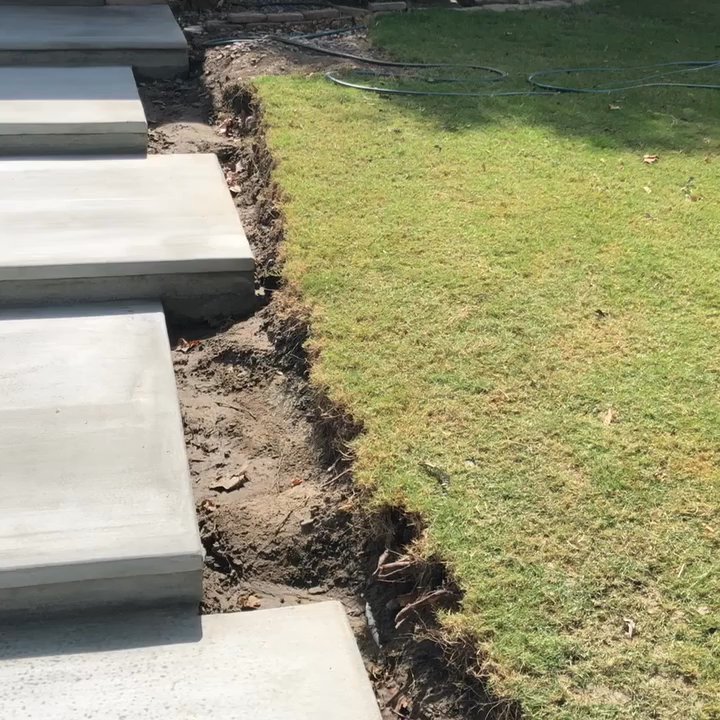 Camarena Landscapes - a wall built here, preferably solid mid century dark grey smooth cement that separates the grass from the steps. plants throughout the yard - Landscaping Near Me