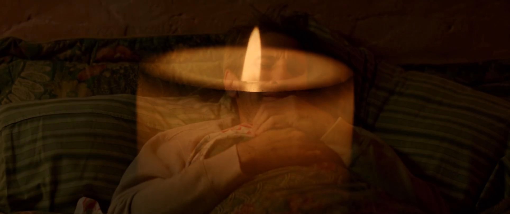 A man experiences profound grief and sorrow in the dim light of his home, transitioning from quiet reflection by a candle to weeping in bed. The scene captures his solitary emotional struggle and distress during a vulnerable moment.