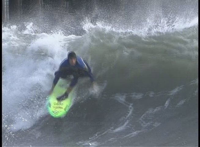 A surfer executes various technical maneuvers on large ocean waves while wearing a wetsuit. The footage highlights skill and movement within a turbulent marine environment.