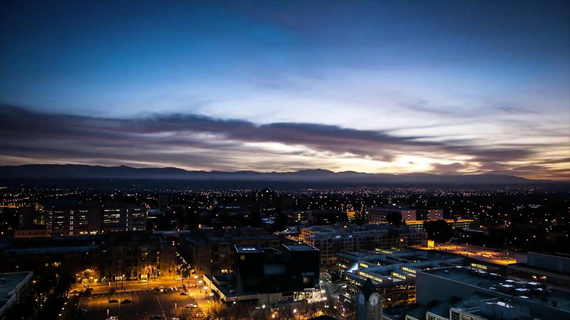 A man and a woman engage in a serious conversation before a transition to a time-lapse of a sunrise over a city skyline, concluding with the woman seated in a restaurant.