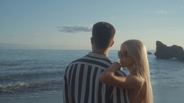 An attractive couple standing side by side on the beach