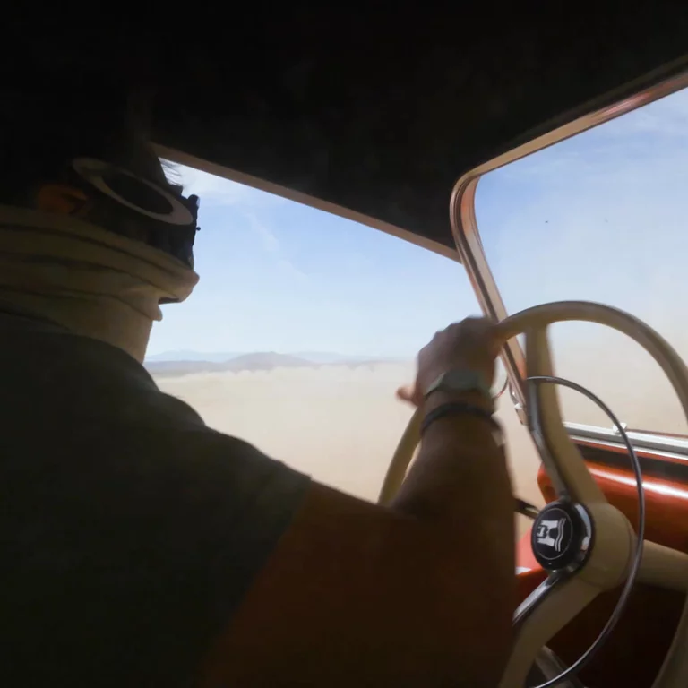 Video of man driving custom car from inside looking out at desert landscape