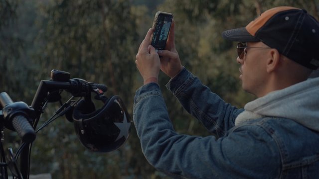 A motorcyclist taking photos of nearby pine trees