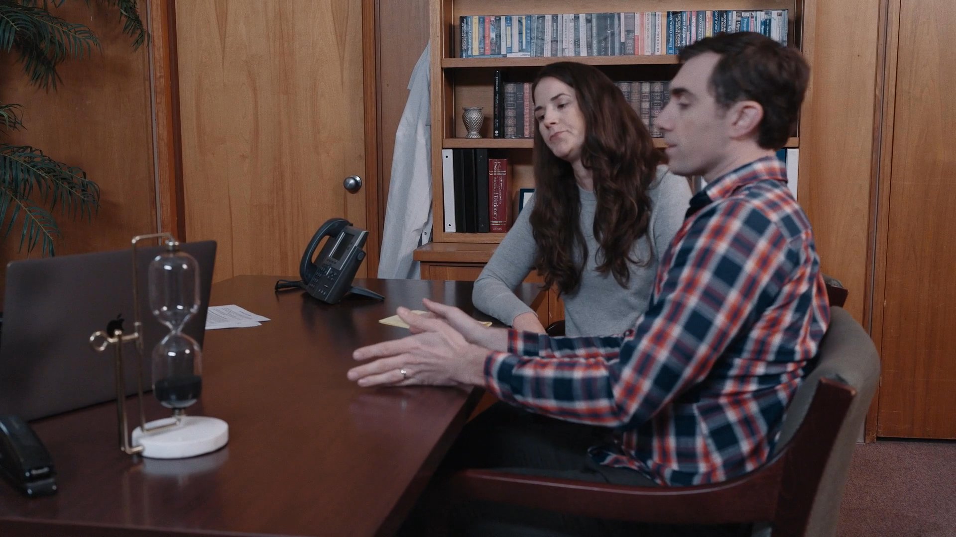 Two professionals engage in a focused business discussion while seated at an office desk. They communicate and collaborate throughout their meeting in a formal setting.