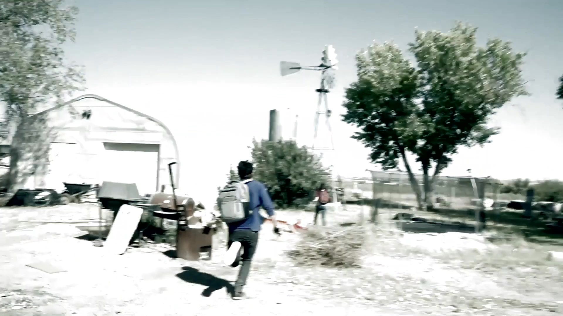 Two individuals run through an outdoor, rural property and play area in a high-energy chase sequence. The camera captures fast-paced, handheld movement as they navigate between structures and open space.