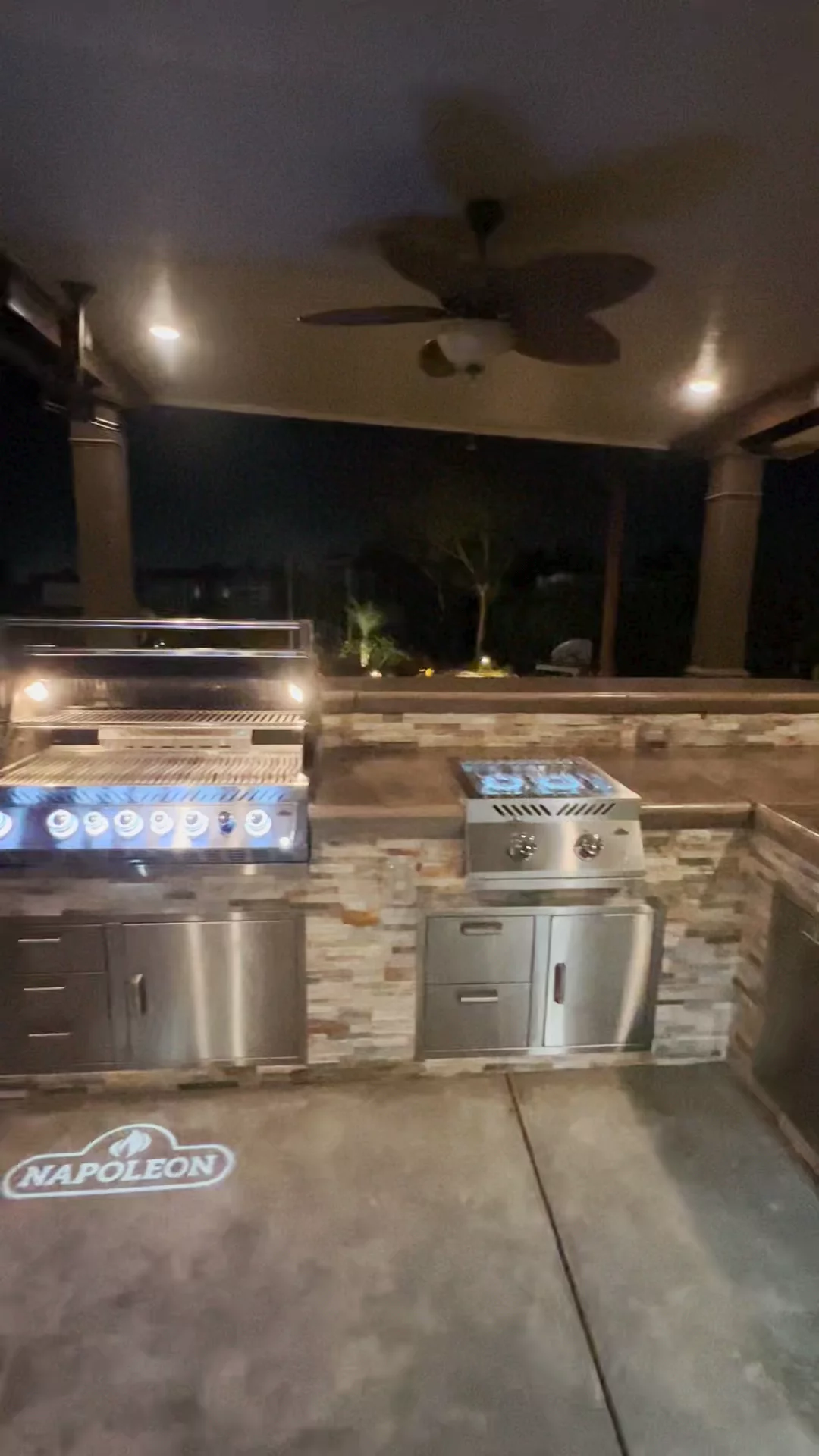 Outdoor kitchen with led lighting, stone veneer base, and built-in grill, sink, storage, and smoker