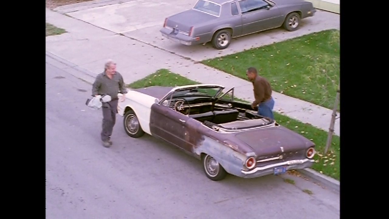 Two men exit a suburban home, walk to a vintage convertible parked on the street, and board the vehicle to depart.