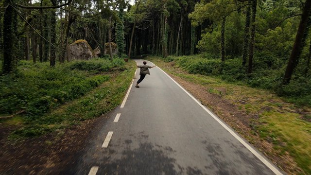 Riding a skateboard on the road in a forest