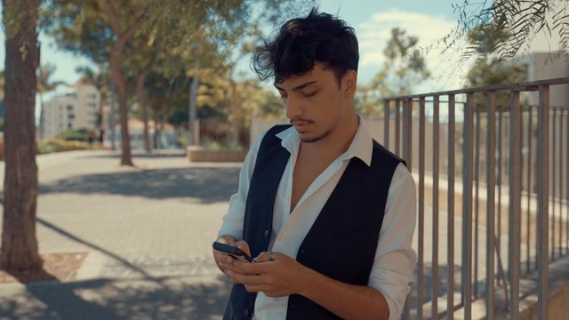 A man calling his friend while standing in the street