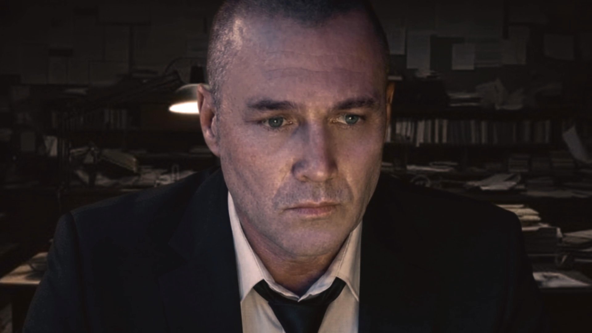 A man in a suit works intensely on a laptop within a dimly lit, cluttered office, suggesting a high-stakes or investigative atmosphere. The scene transitions to show a woman in a different environment, implying a connection or surveillance narrative.