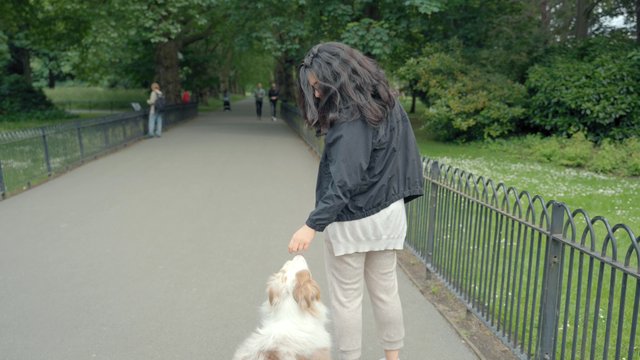 A woman feeds her dog a treat in the park
