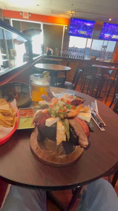 Molcajetes - This is a small Molcajete in the foreground, surrounded by chips, salsas, tall beer, old fashioned, charro beans - Buffets Near Me - Del Rio, Texas