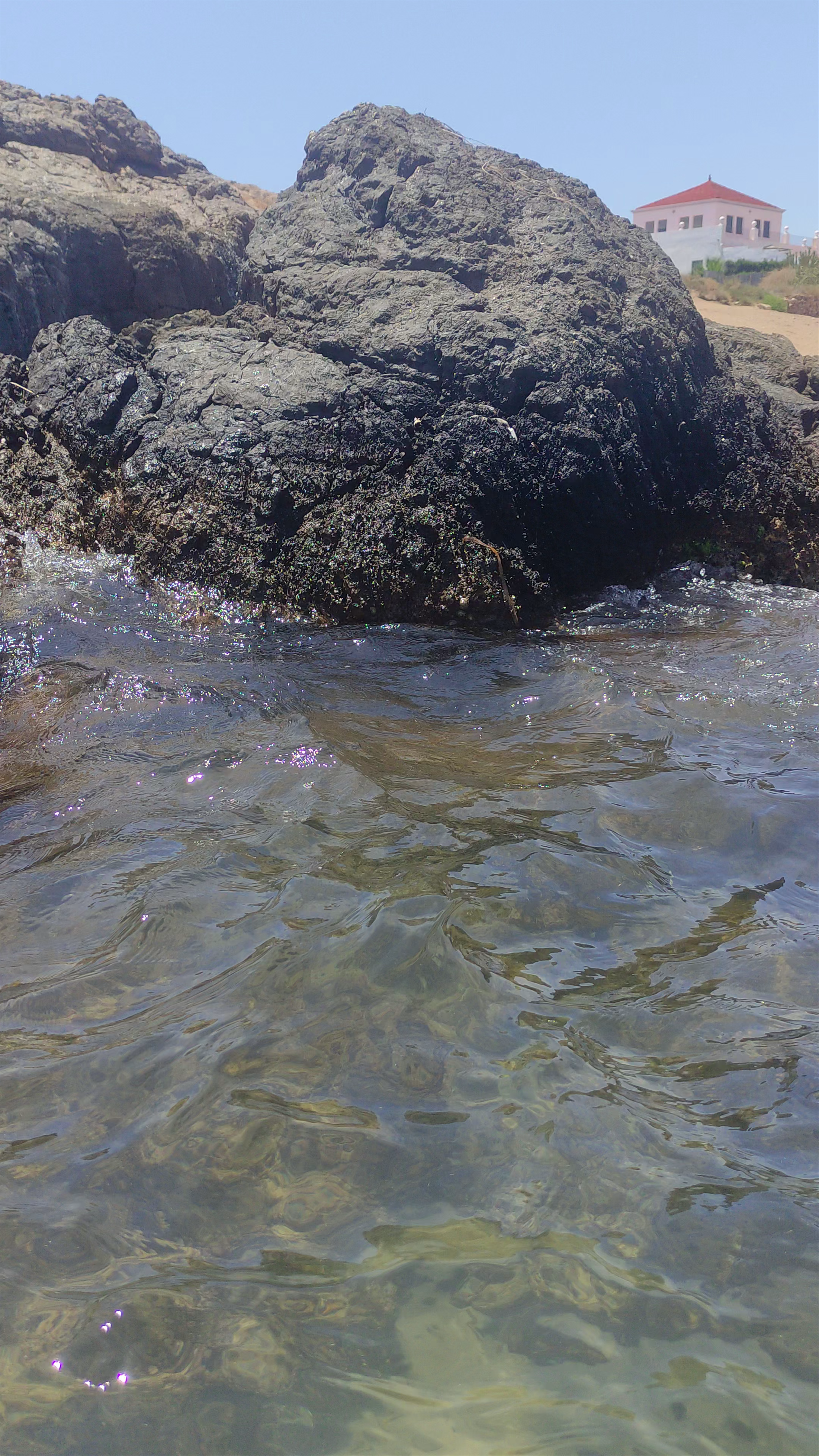 Sunlit Serenity at Playa de la Pava, Spain: Rocky Shore & Crystal Clear Waters