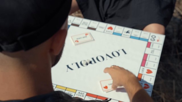 A man draws a game card with the text "Give a compliment"