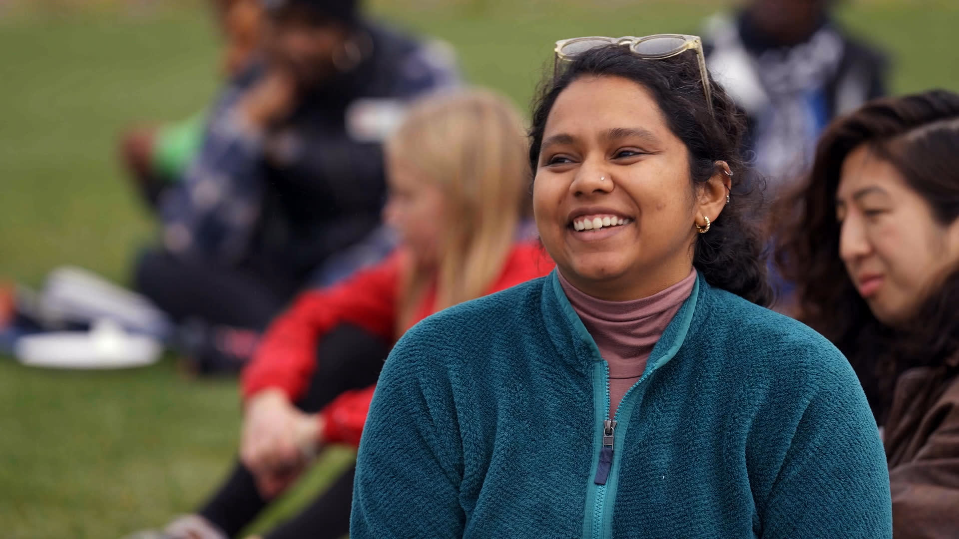 Participants sit together outdoors as several people take turns speaking and sharing a warm moment of gratitude. The gathering closes with thanks and a mention of more plants to be planted.
