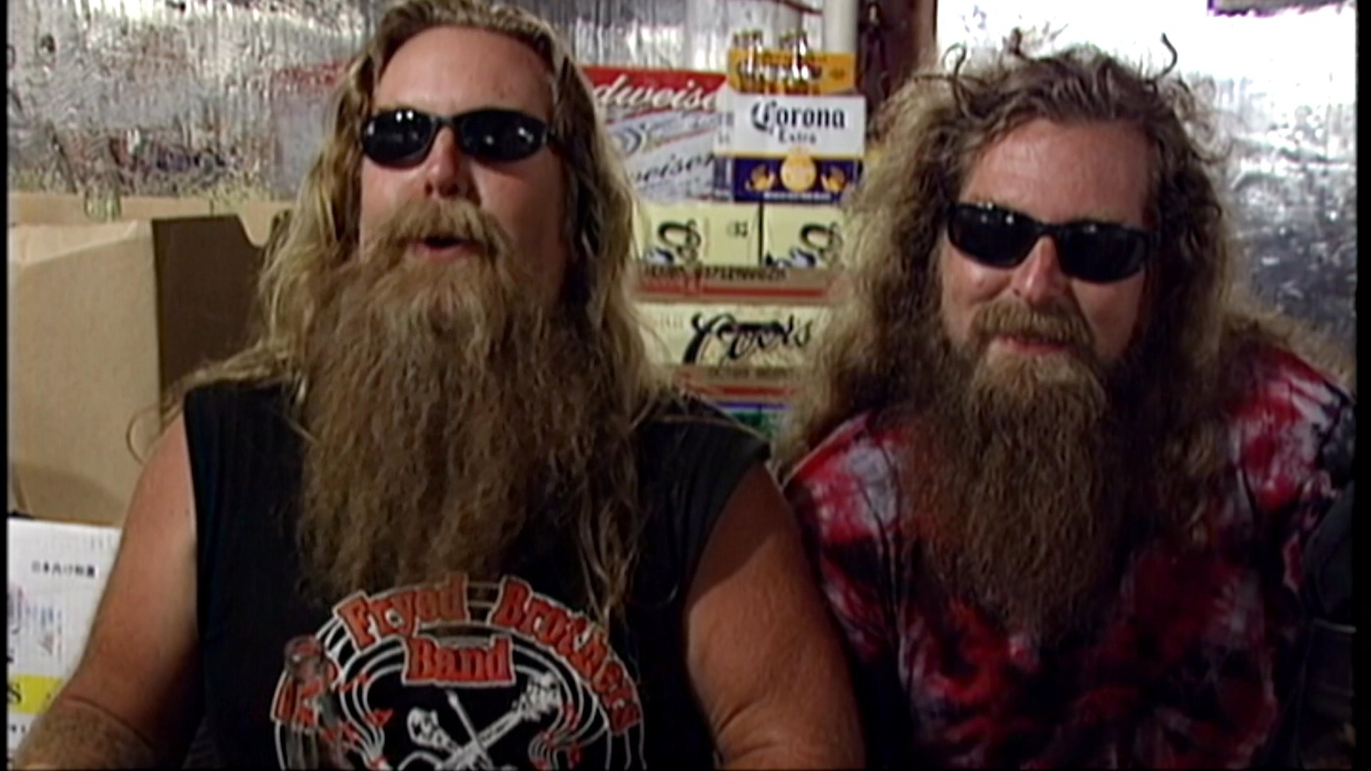 Two long-bearded musicians wearing sunglasses discuss their music and career during an informal interview setting.