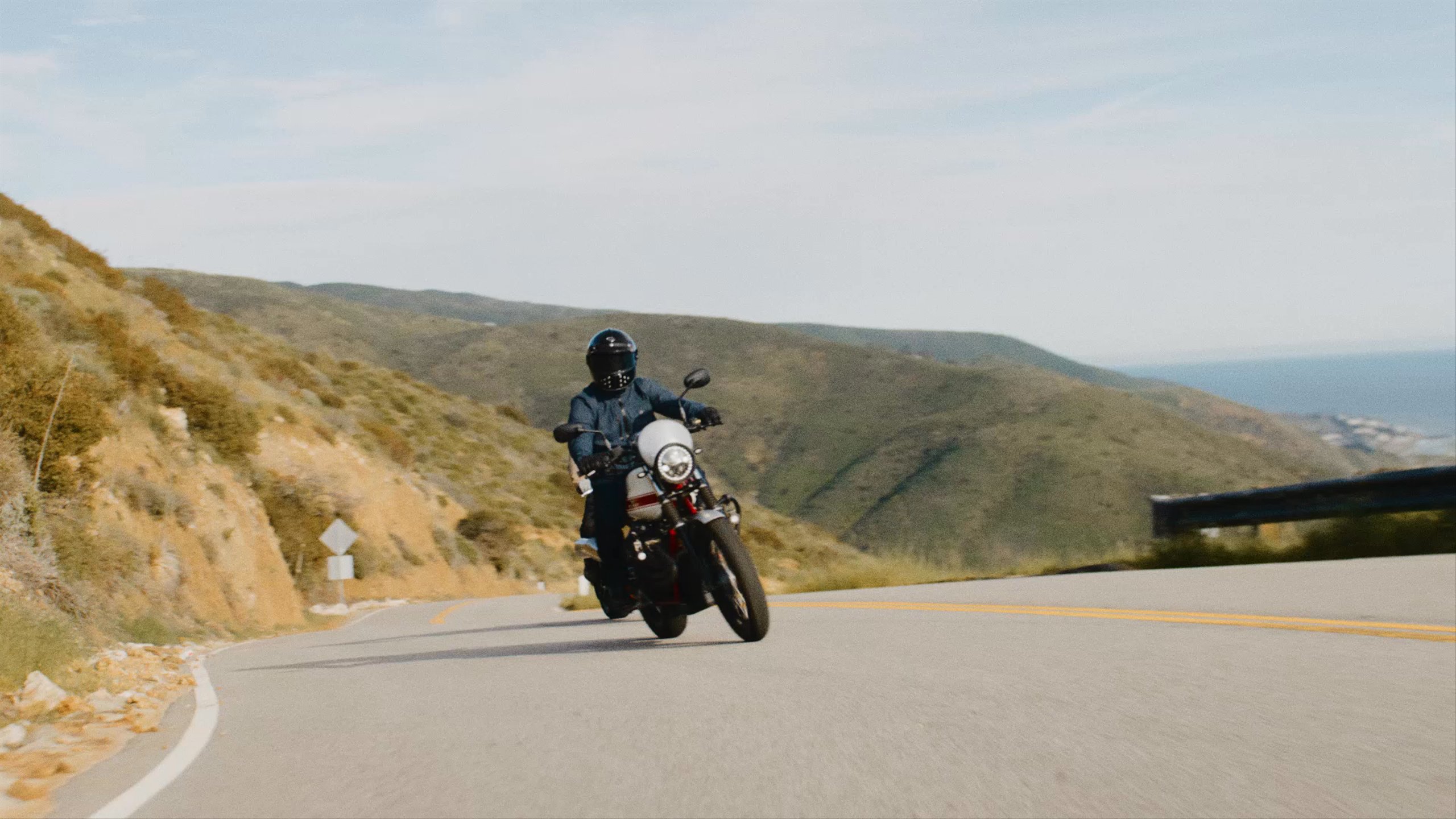 Video of two motorcyclists riding up Malibu hills with Pacific Ocean in the background