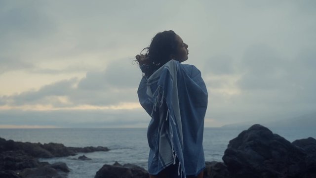 A girl drying her hair with a towel near the sea.