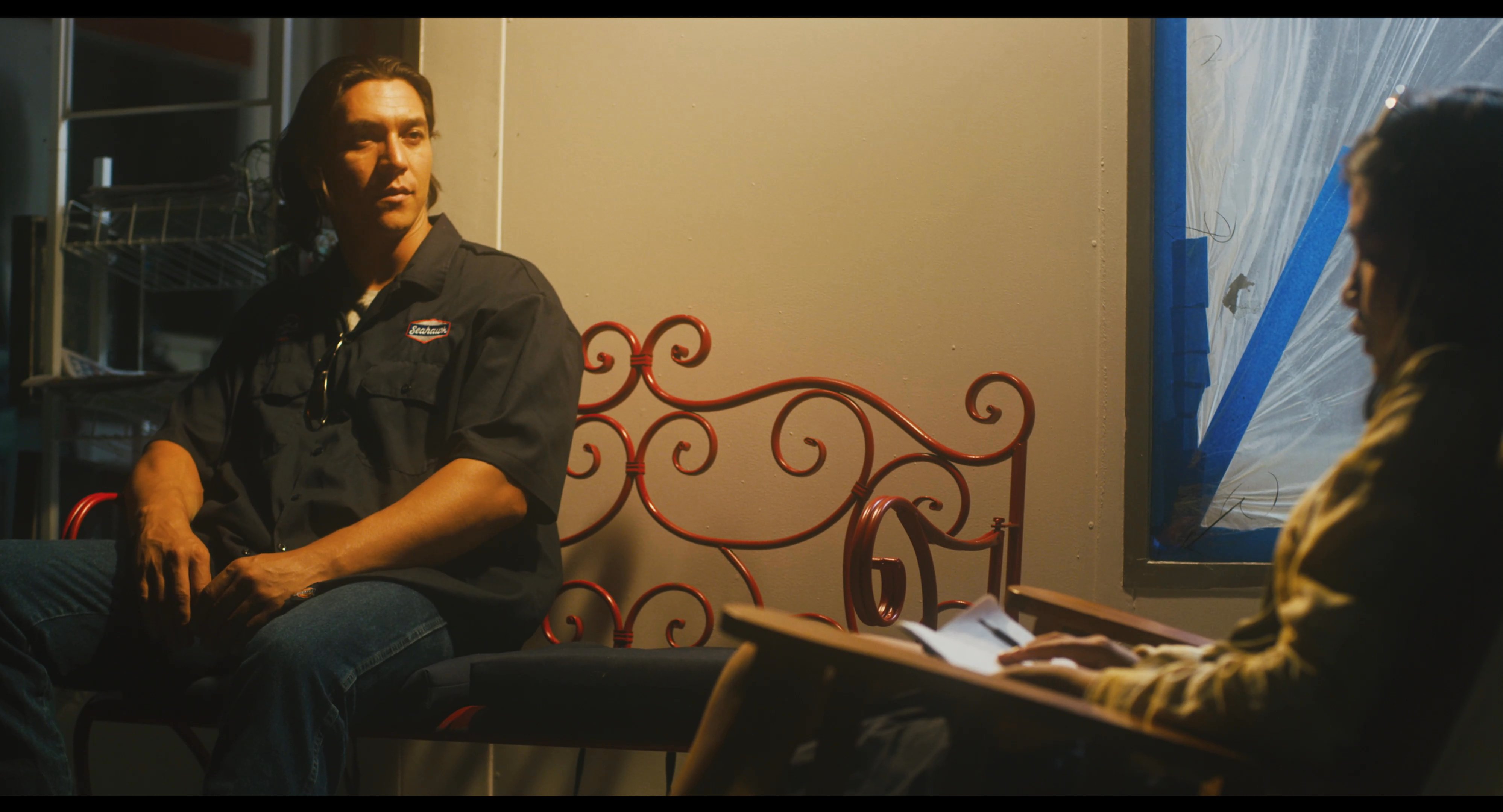 Two individuals sit in chairs while engaged in a thoughtful dialogue. The warm, dimly lit environment highlights their focused interaction and exchange of information.