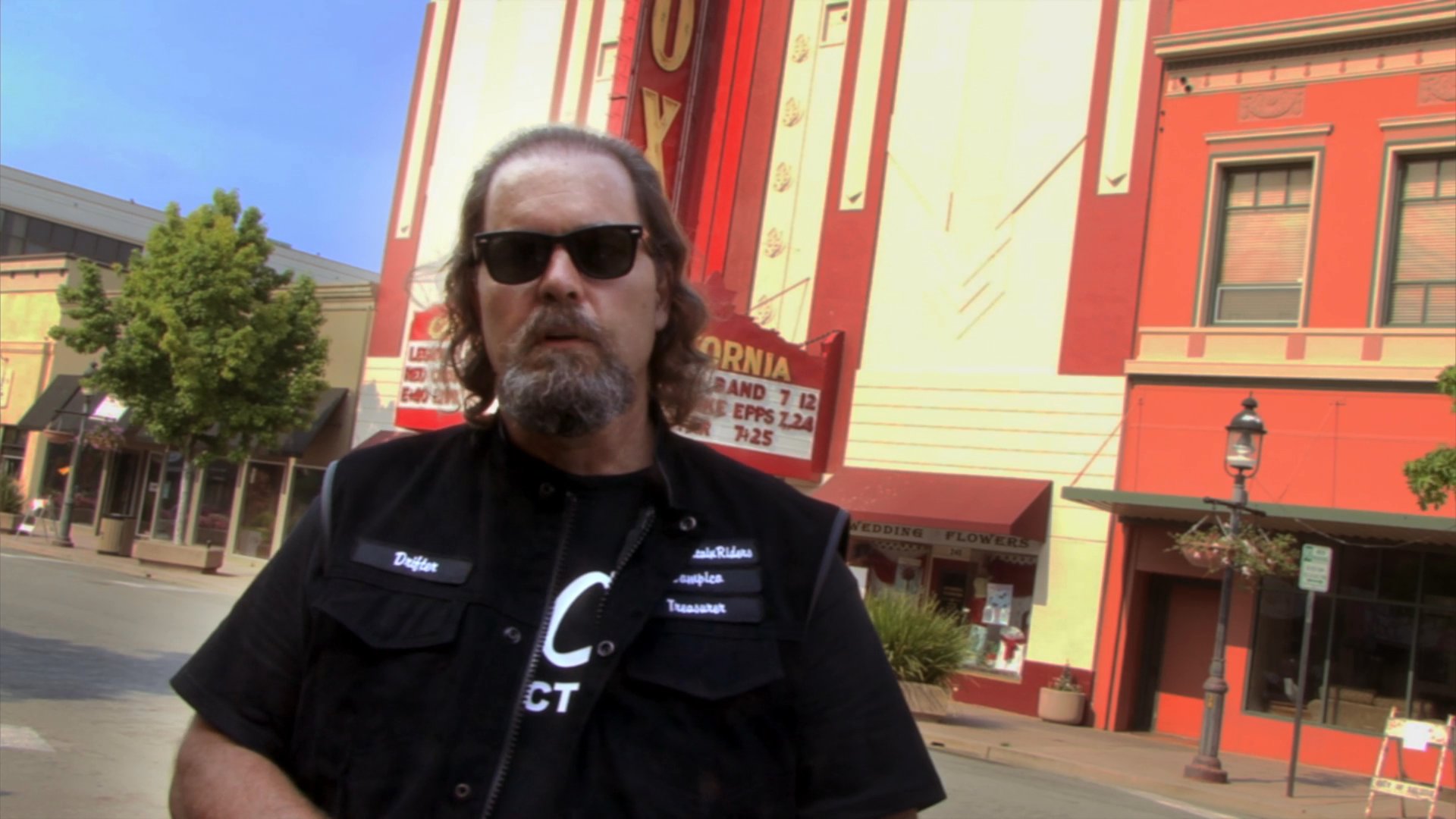 A man describes his experience as a mounted police officer while patrol members on horseback ride past the historic California Theatre in the background.
