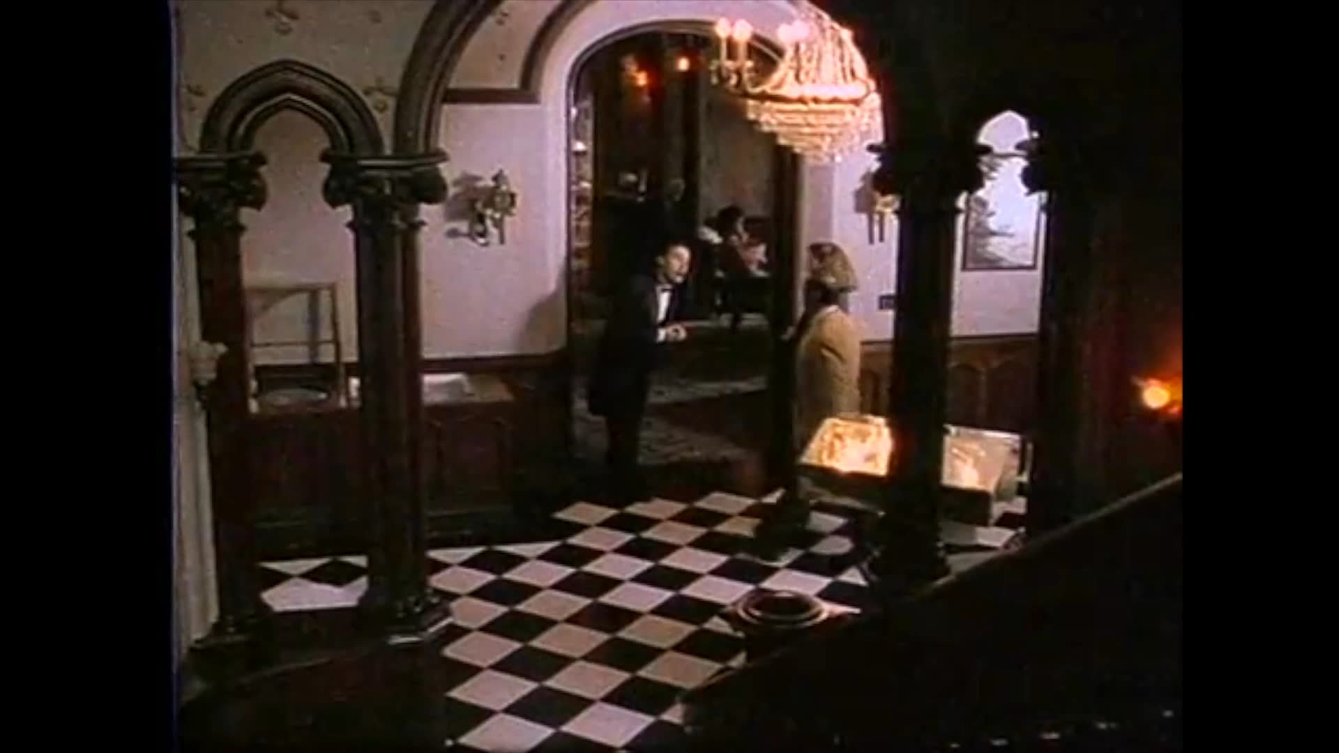 A man in a fedora engages in an intense, sepia-toned exchange before the scene transitions to a formal restaurant where individuals navigate a complex social or investigative situation involving a man in a wheelchair.