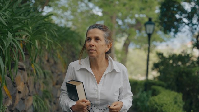 A religious woman walks in a garden