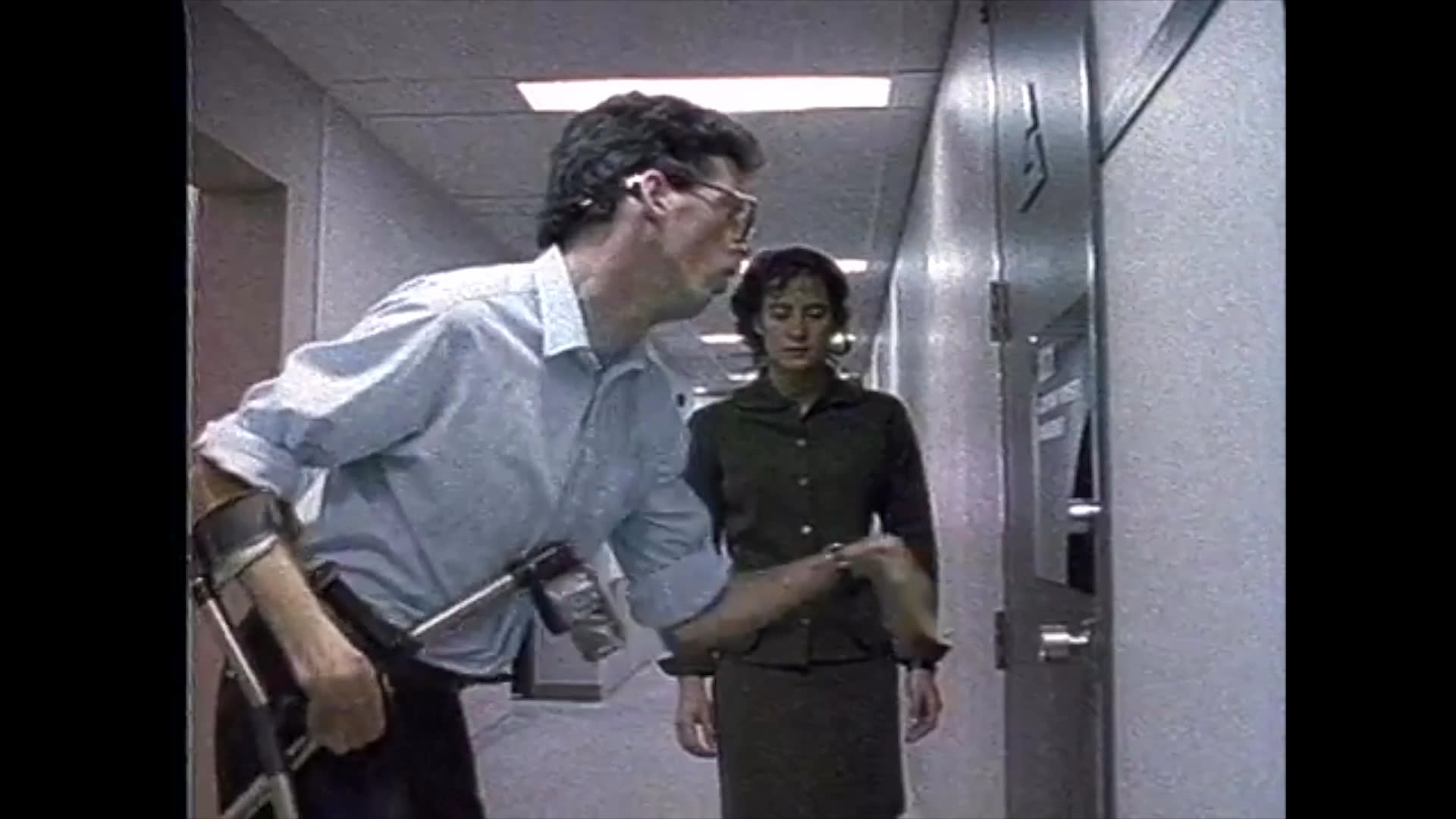 A man using forearm crutches navigates a modern office hallway, accompanied by a colleague who opens a door for him. The sequence concludes with a close-up of a woman observing the environment.