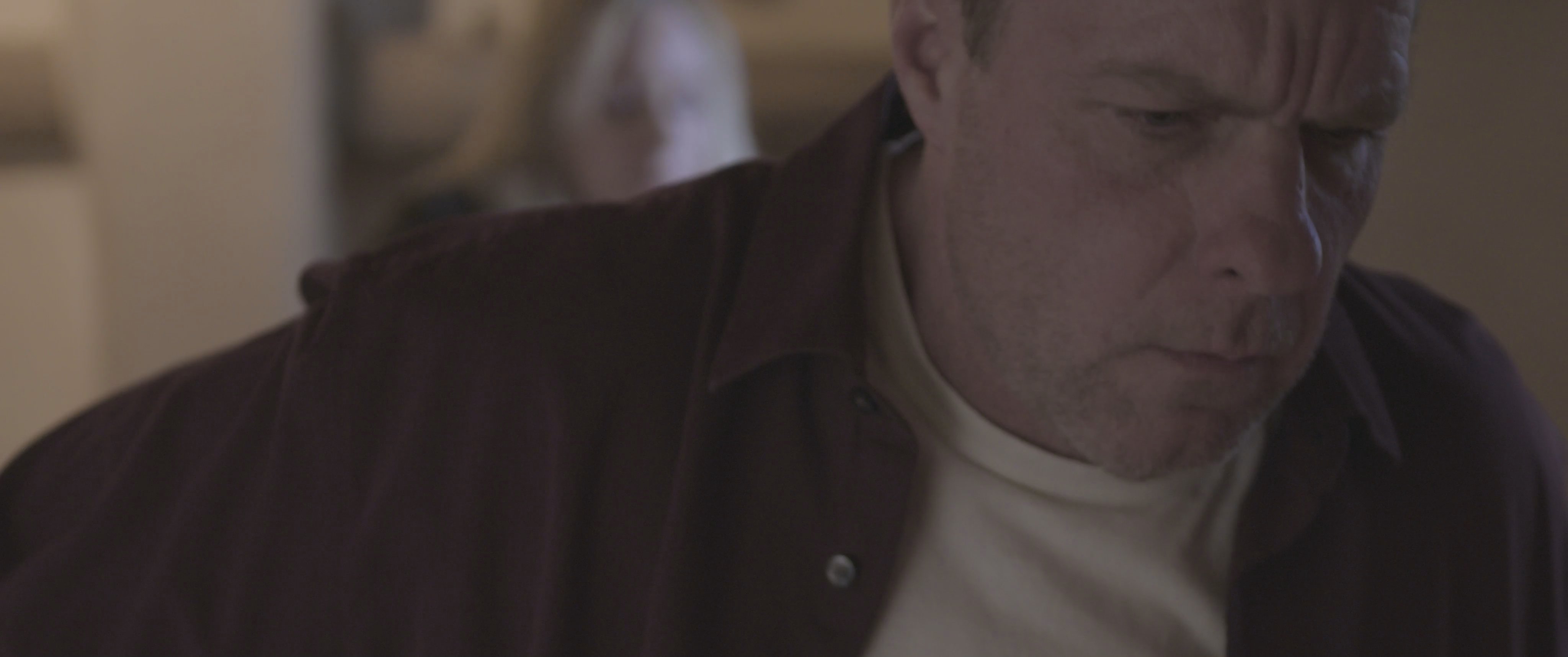 A tense encounter unfolds in a residence as a man draws a handgun while a woman observes, creating a high-stakes, threatening atmosphere.