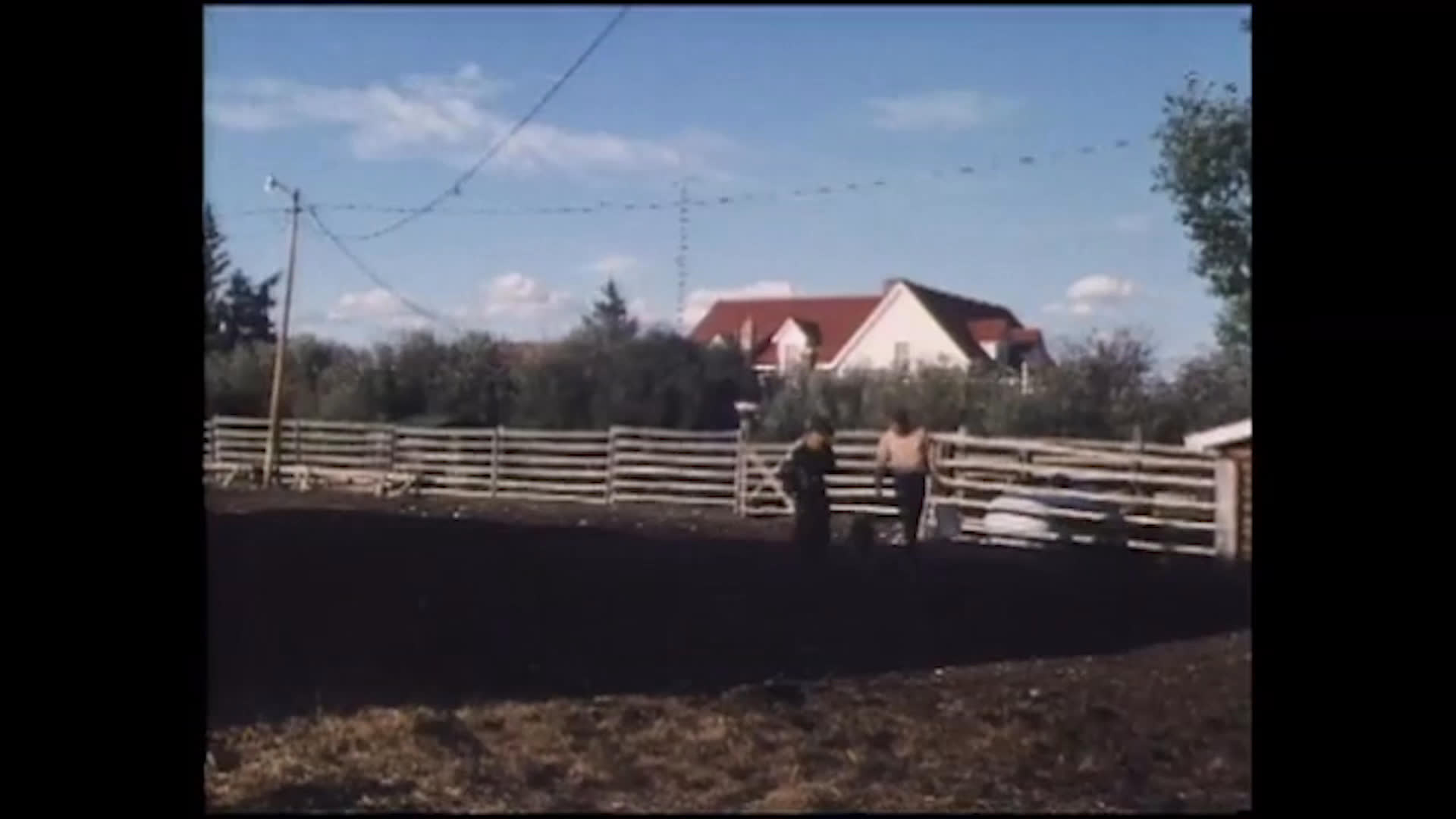 A ranch worker tends an animal in a fenced corral as others walk across the rural property. She says working every day takes a toll on her personal life and relationship, while Richard is understanding.