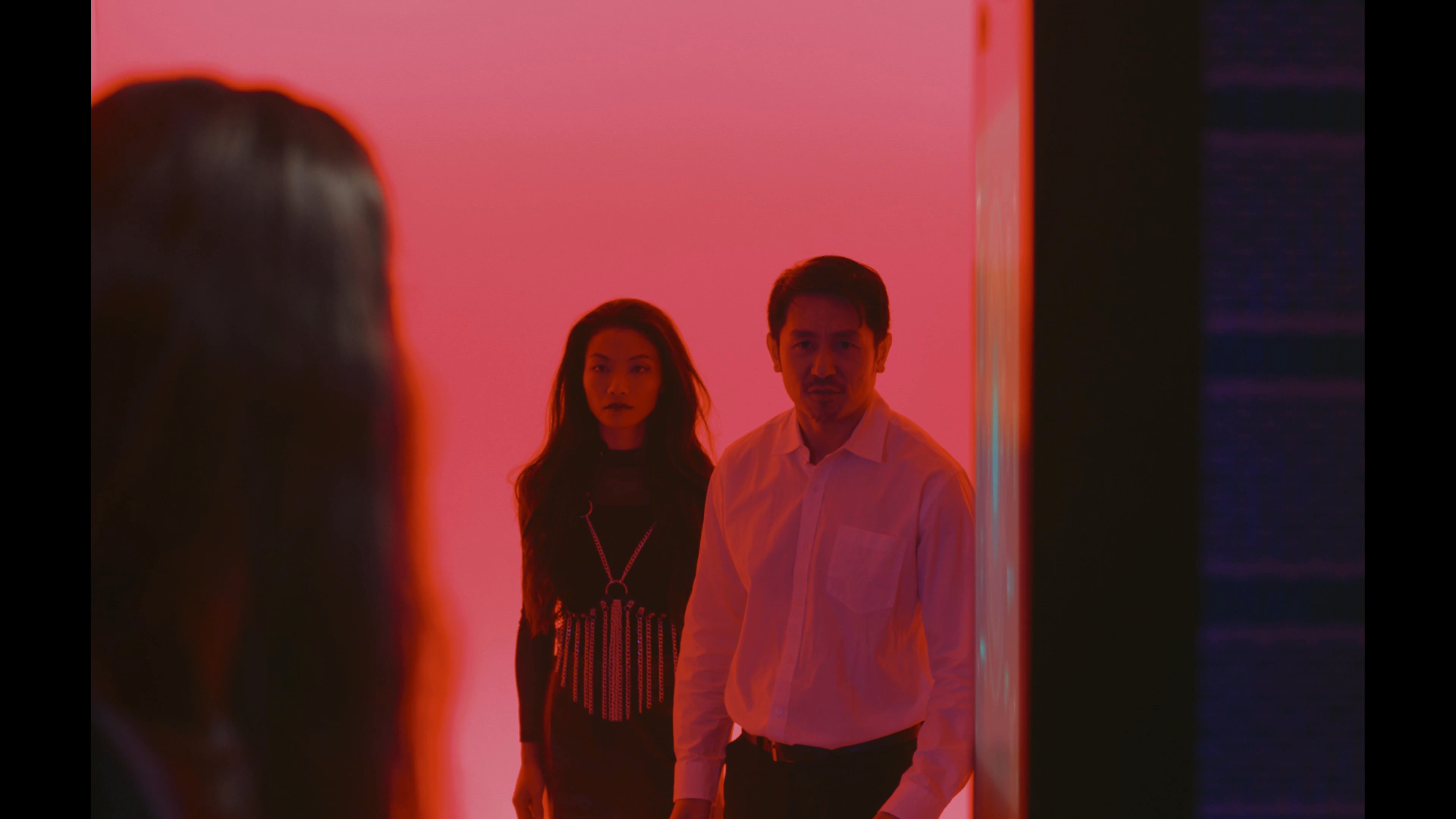 An individual interacts with a cybernetically enhanced woman inside a brightly lit server room. The scene depicts a tense exchange within a high-tech facility environment.