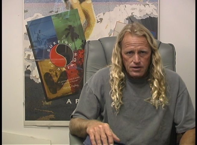 A long-haired man discusses personal history in a studio setting, interspersed with a still photograph of an elderly woman celebrating with a cake.