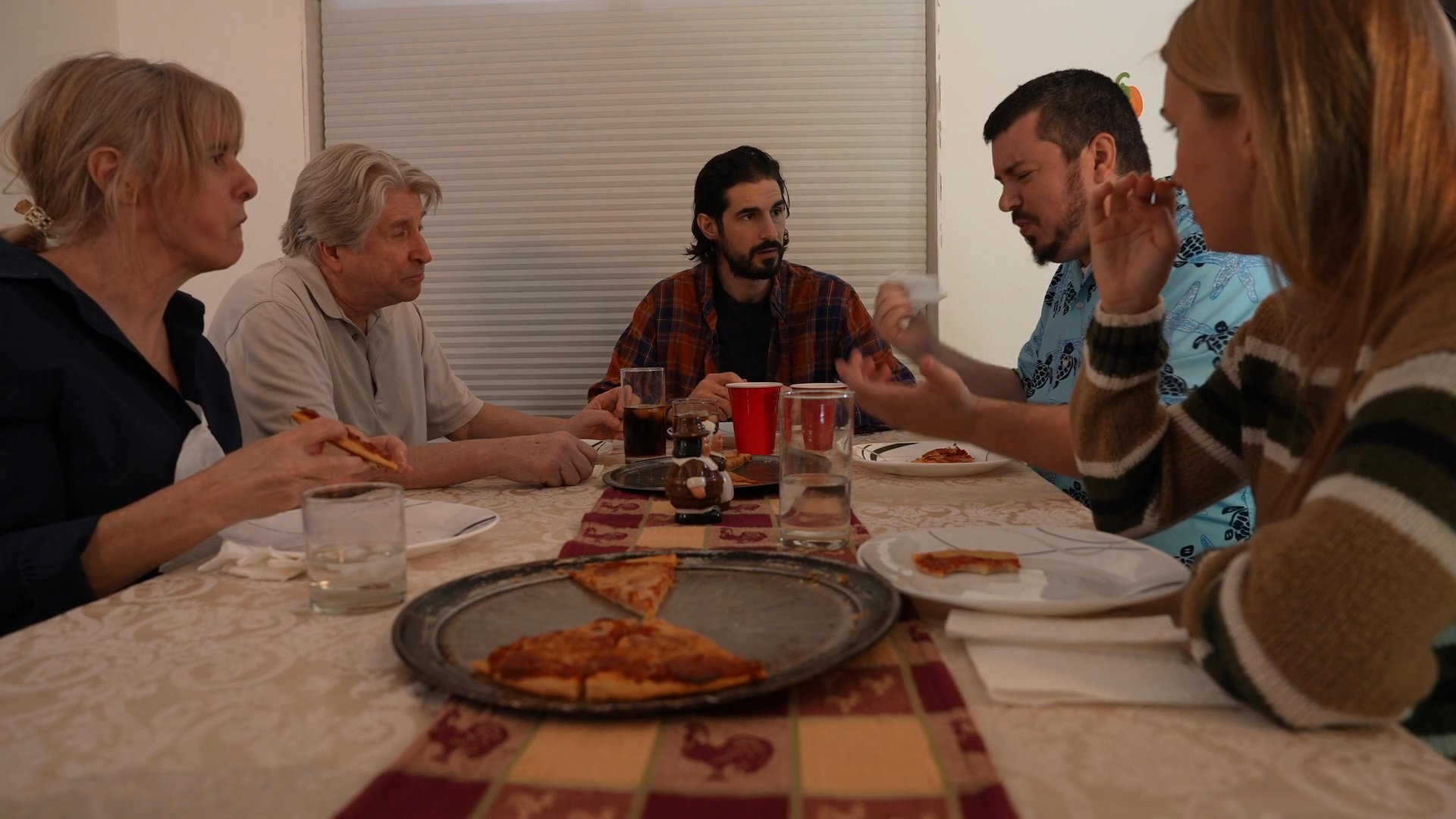 The sequence transitions from introductory credits featuring sports announcers and a rooster to a group of actors sharing a meal at a dining table, followed by final production credits.