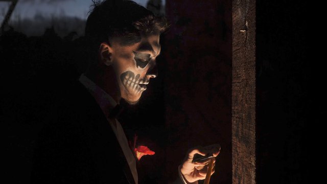 Man with skull makeup lights a candle