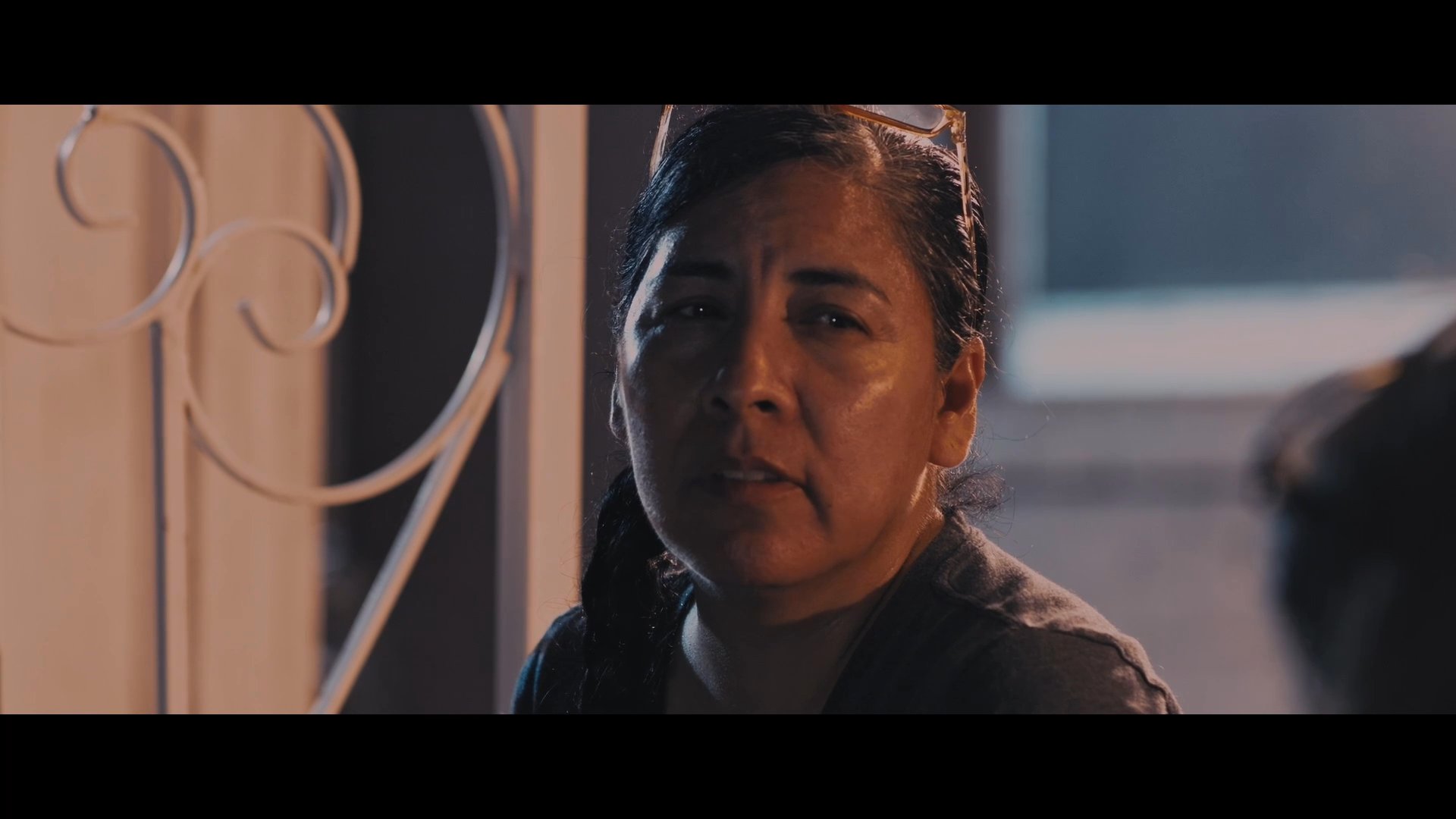 A mother and daughter sit outdoors at dusk, engaging in a tense, serious conversation regarding a personal disagreement.