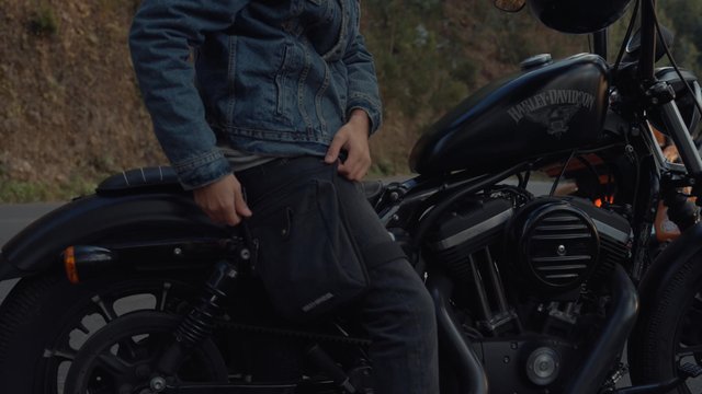 A motorcyclist getting his wallet and credit card out of his bag