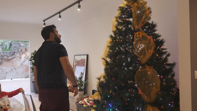 Man adjusts Christmas tree decorations