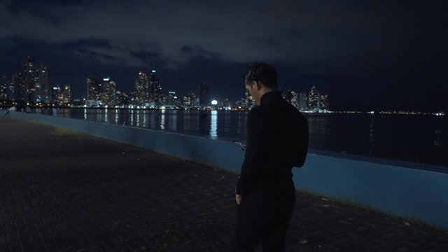 Asian man walking next to a river quay