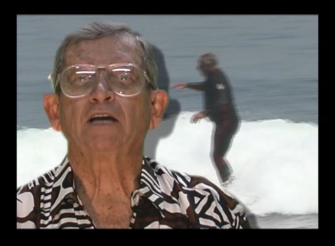 An experienced surfer discusses his craft while archival footage of him riding ocean waves plays as an overlay. The segment highlights personal expertise and the physical activity of surfing.