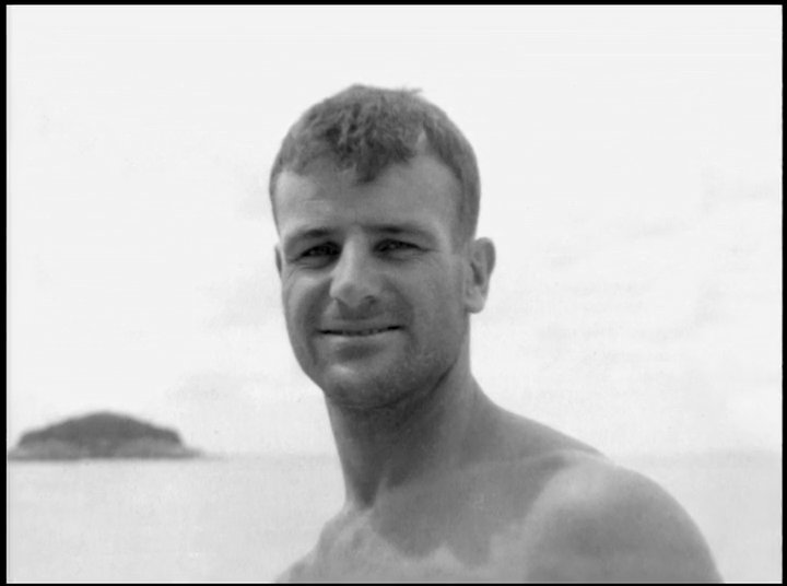 Historical archival footage of early tandem surfing transitions into modern big-wave surfing, illustrating the progression of the sport over time.