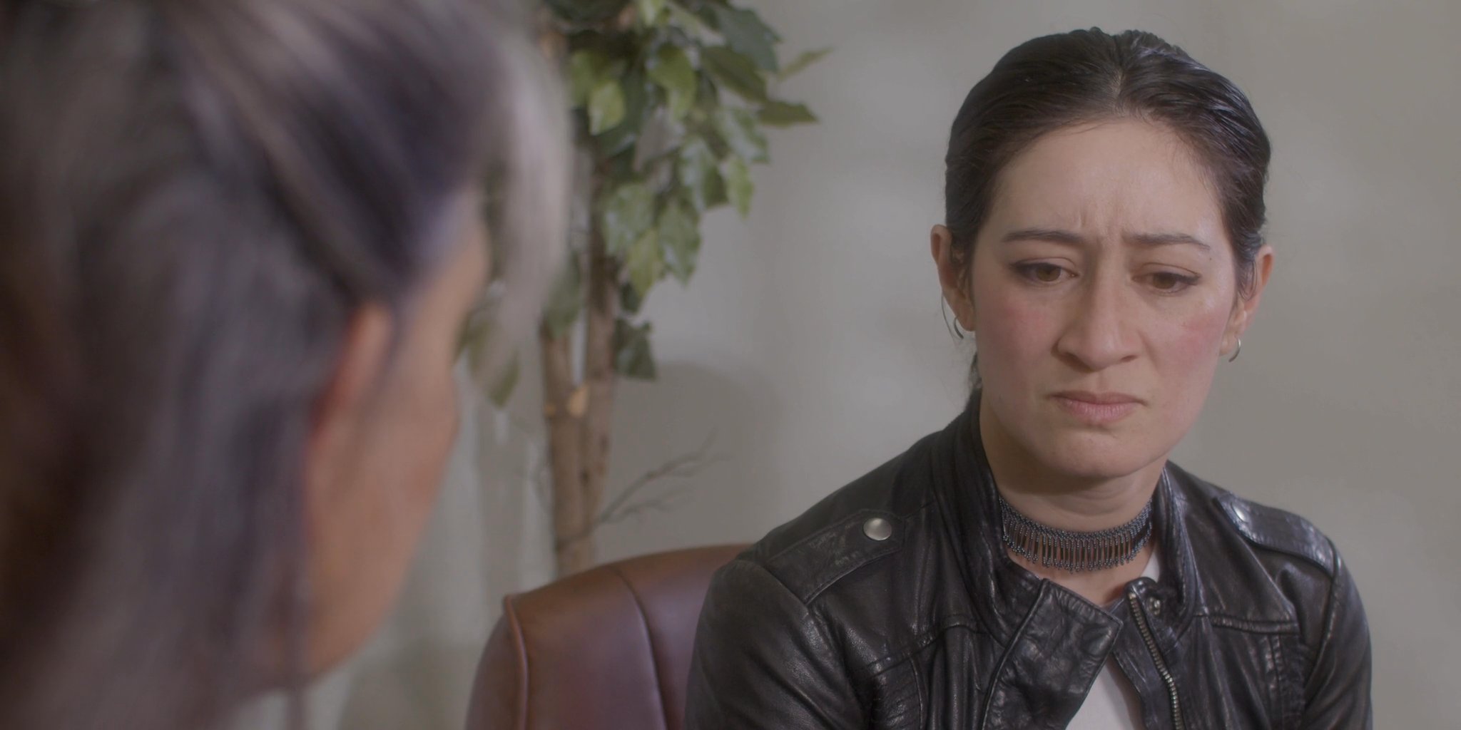 An older woman engages in a compassionate conversation with a younger woman, providing emotional support and reassurance through physical touch.