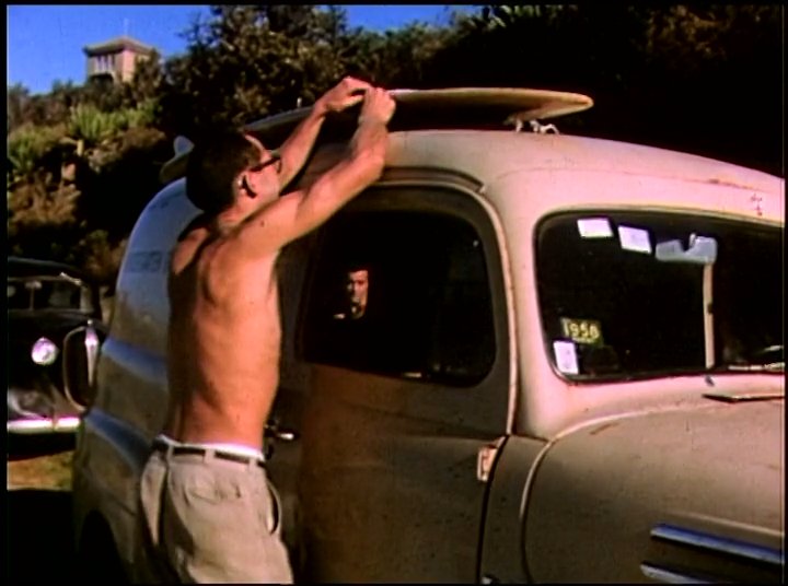 Surfers load boards onto a classic van before transitioning to action shots of them riding waves in the ocean.