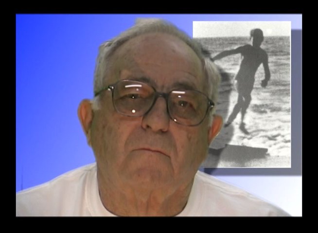 Harry Mayo shares personal reflections while a vintage photograph of himself surfing is displayed in the background. The interview format focuses on his history and experiences as an athlete.