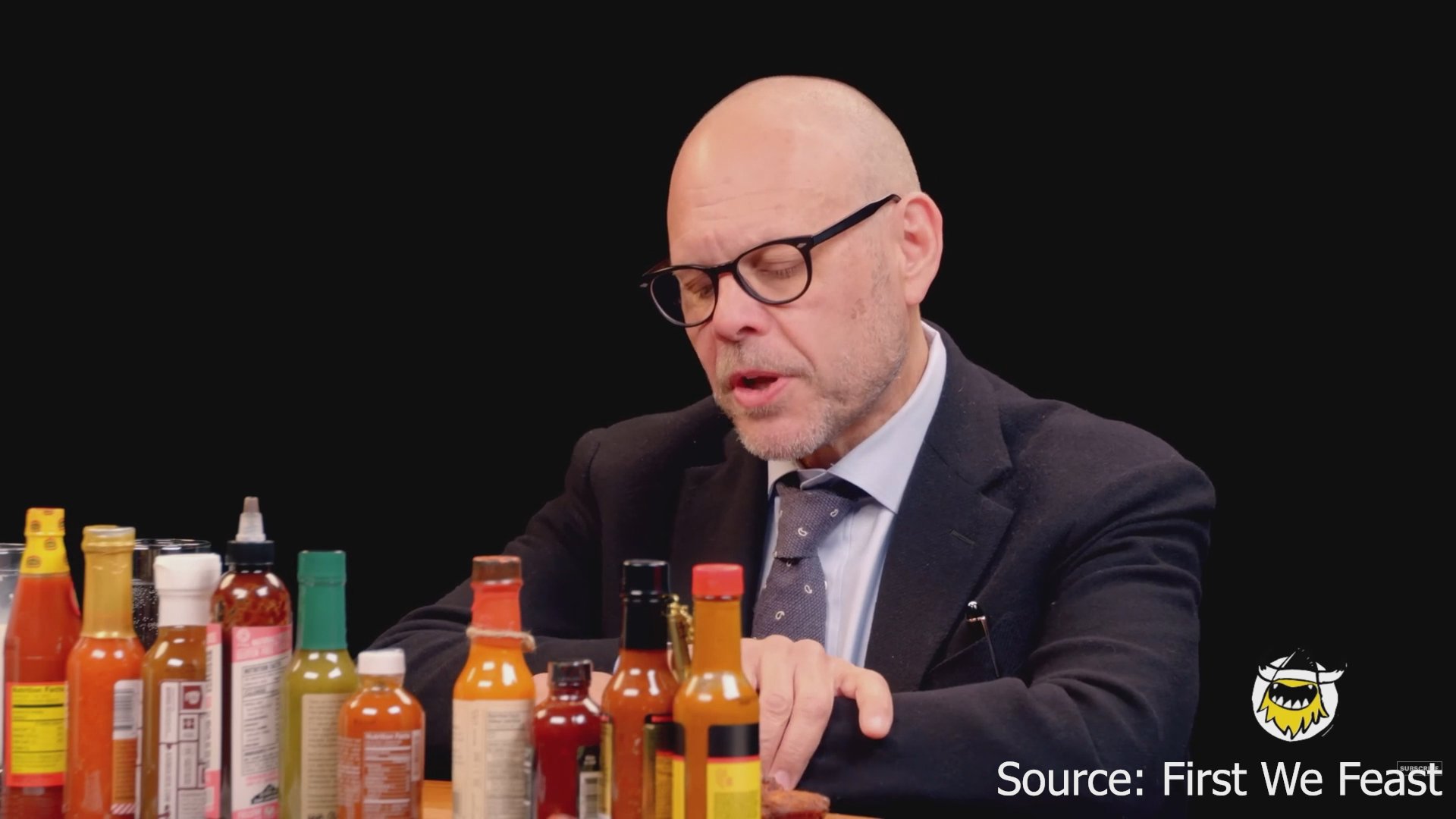 Host Sean Evans conducts a discussion featuring archival television coverage of the September 11 attacks, transitioning to a sit-down interview with a guest involving hot sauce and chicken wings.