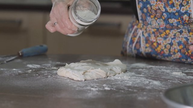 Woman sprinkling flour on dough